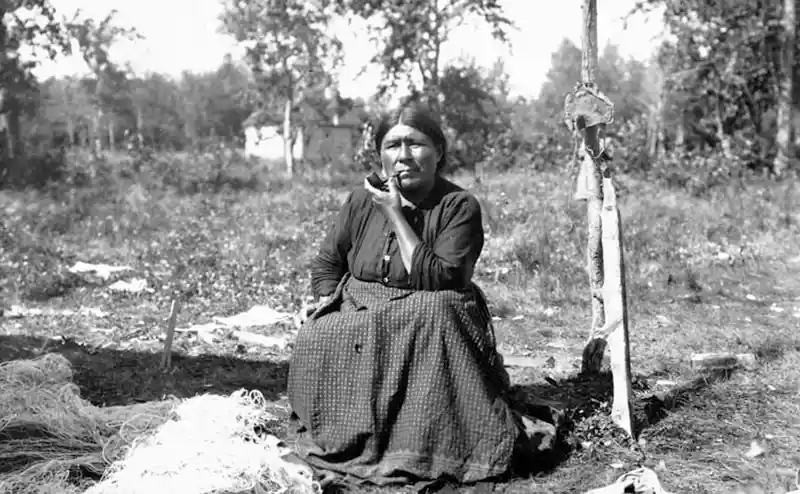 A First Nations woman smoking a pipe, taken close to what is currently Manitoba, CA. c1900-1910